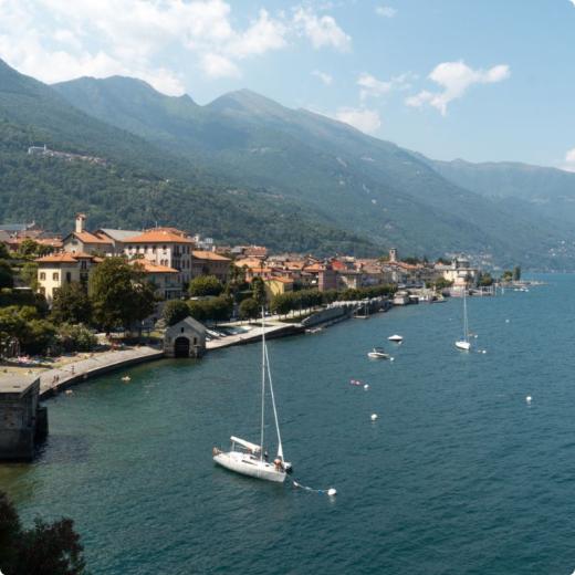 Vista panoramica di un lago con barche e montagne sullo sfondo.