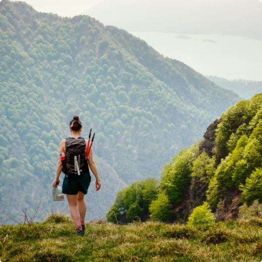 Escursionista con zaino e mappa, cammina su un sentiero di montagna panoramico.